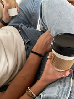 a man laying on his stomach holding a cup of coffee