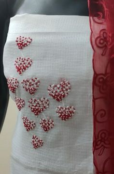 a white dress with red hearts on it and a red scarf hanging from the back