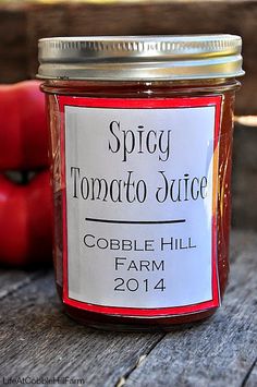 a jar of tomato sauce sitting on top of a wooden table next to an apple