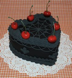 a chocolate cake with cherries on top is sitting on a doily covered table