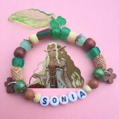 made by Yumestar.chr! a cute bracelet inspired by Sonia from Tears of the Kingdom. Bring a small piece of Queen Sonia with you, with the colors of her Zonai dress, and flowery accents for her personality 💚🌿 Adjustable Fantasy Bracelets As Gift, Themed Green Beaded Bracelets As Gift, Themed Green Beaded Bracelets For Gifts, Green Themed Beaded Bracelets As Gifts, Fandom Style Personalized Jewelry Gift, Personalized Fandom Jewelry Gift, Adjustable Fandom Bracelets As Gift, Adjustable Beaded Bracelets For Fandom Gifts, Zelda Bracelet