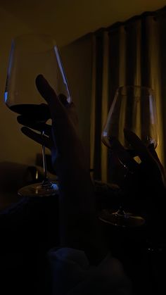 two people holding wine glasses in their hands with the light shining on them and curtains behind them