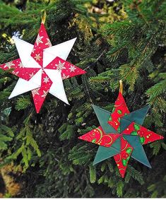 two red and white paper stars hanging from a christmas tree