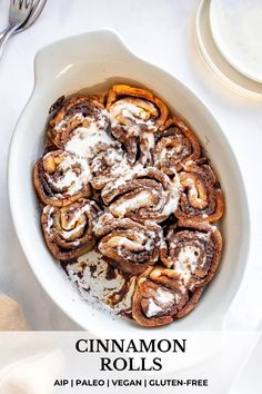 cinnamon rolls in a white bowl with powdered sugar on top