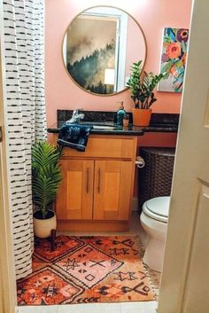 a bathroom with a sink, toilet and mirror in it's corner next to a potted plant