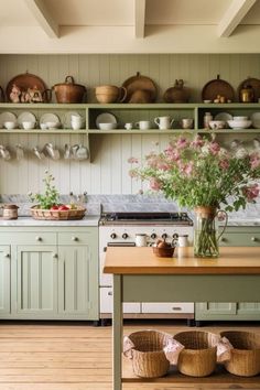 a kitchen filled with lots of green cabinets and counter top covered in baskets next to a wooden table