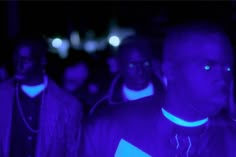 a group of men standing next to each other in front of a purple light at night