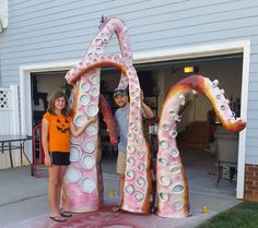 two people are standing in front of a large sculpture that looks like the letter a