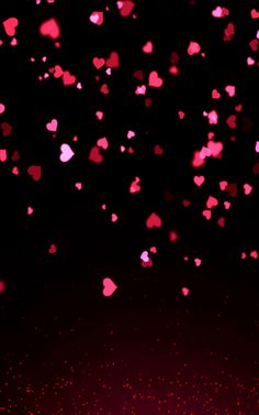 pink hearts floating in the air against a black background with red glitter flecks