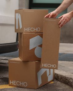 three cardboard boxes stacked on top of each other in front of a van with the words hecho written on them