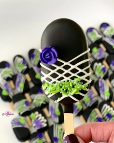 a hand holding a chocolate lollipop with green and purple decorations on it's stick