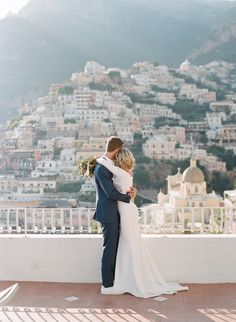 a bride and groom embrace on the balcony of their wedding venue in positi