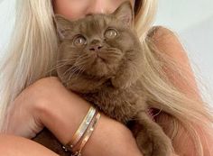 a woman holding a cat in her arms and looking at the camera with an intense look on her face