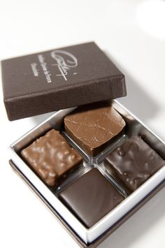 four different types of chocolates in a box on a white surface with the lid open