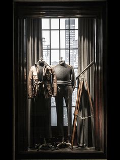 two mannequins are standing in front of a window with a pair of leather jackets on display