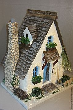 a small model house with a stone chimney and tiled roof is displayed on a table