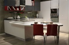 two red chairs sit at a table in the middle of a kitchen with an island