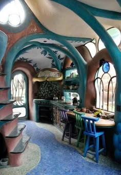 the inside of a house with blue and pink walls, arched windows, and colorful furniture