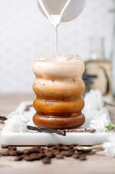 coffee being poured into a cup on top of two stacked donuts with white icing