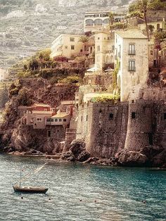 a boat floating on top of a body of water next to a rocky cliff covered hillside