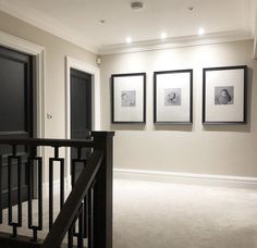 an empty room with pictures hanging on the wall and stairs leading up to another room