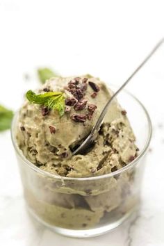 a small glass bowl filled with ice cream and mint garnish on a marble surface