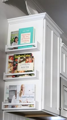 a kitchen with white cabinets and shelves filled with magazines