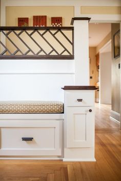 a white bench with drawers underneath it in a room that has hardwood floors and walls