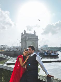 a man and woman standing next to each other near the water