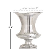 a silver vase sitting on top of a white table next to a measuring line with the measurements