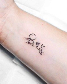 a person with a small tattoo on their arm that has an image of a dog and cat