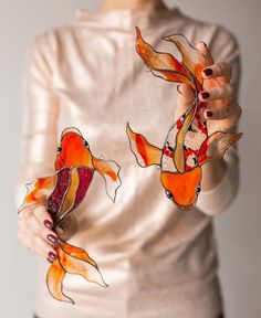 a woman holding two orange fish in her hands