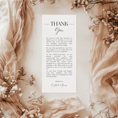 a thank card surrounded by flowers and fabric