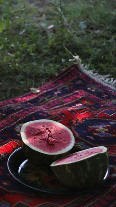 a watermelon cut in half sitting on top of a plate next to another piece of fruit