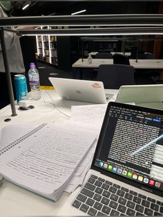 an open laptop computer sitting on top of a desk next to a notebook and pen