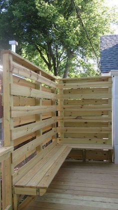 a wooden bench sitting on top of a wooden deck next to a fenced in area