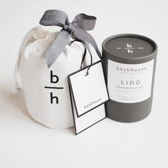 a bag with a tag next to it and a small candle in the pouch that says, backhouse