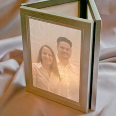 an image of a man and woman in a photo frame on a bed with white sheets