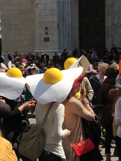 people are standing in front of a building with fried eggs on their heads and holding cell phones to their ears