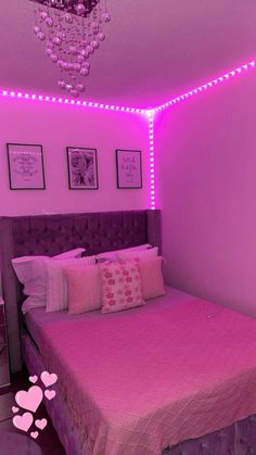 a bed with pink sheets and pillows in a room that has purple lights on the walls