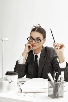 a woman sitting at a desk with a pen in her hand