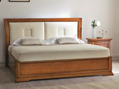 a bed with white sheets and pillows in a room next to a dresser, lamp and pictures on the wall