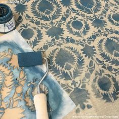 a blue and beige area rug with paint roller next to it