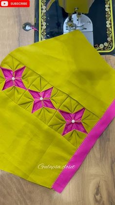 a yellow table cloth with pink flowers on it next to a sewing machine and thread