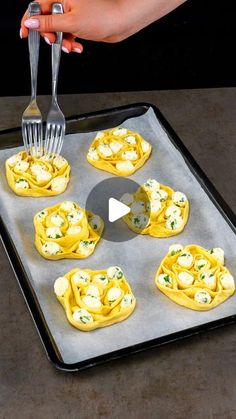 a person is holding a fork over some appetizers on a baking sheet with other food items