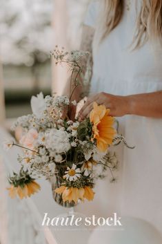 a woman holding a bouquet of flowers in her hand