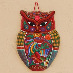 an owl shaped wall hanging on the side of a building with flowers and birds painted on it