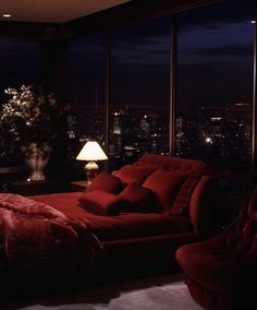 a living room filled with furniture and a large window overlooking the city at night time