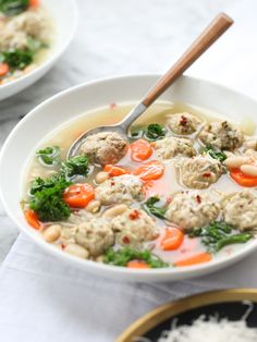 two bowls of soup with meatballs, carrots and broccoli