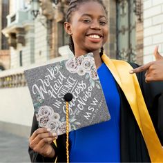 a woman in graduation gown holding up a sign